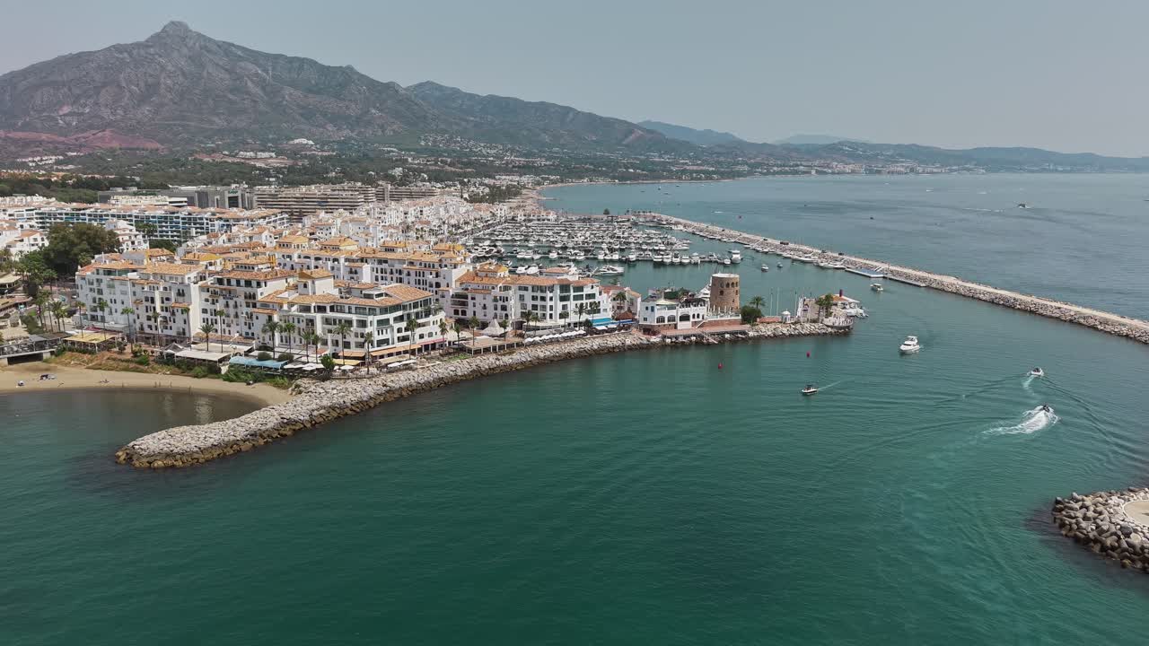 Amazing drone fly over the Marbella's marina with yachts and coastal town by mountain, Málaga, Spain
