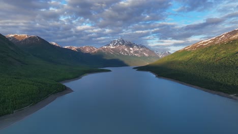 eklutna lake with snowcapped mountains and cloudy sky in anchorage, alaska - aerial drone shot