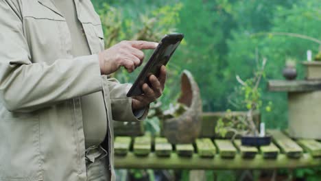 midsection of caucasian male gardener using tablet at garden center