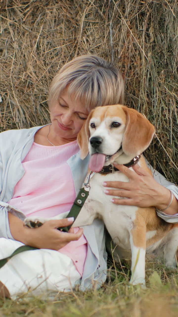 여자는 개를 가까이 붙잡고 애정으로 만지며, 광활한 농지에서  에 혀 평온하고 사랑스러운 순간, 열린 에 둘러싸여 있습니다.