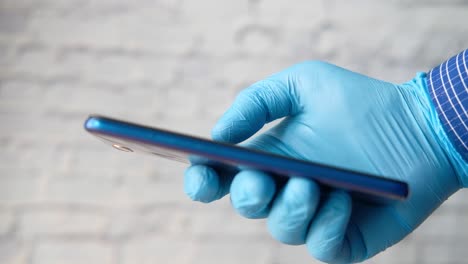 person using smartphone while wearing protective gloves.