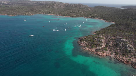 wonderful aerial view and zooming out over sailboats sailing on the island of caprera in sardinia