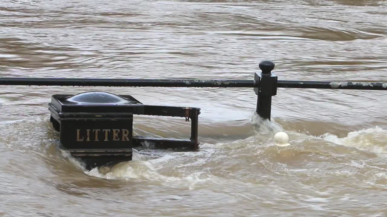 The River Severn during a winter flood flowing over railings and a litter bin