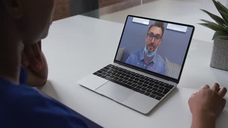 Mid-section-of-african-american-woman-having-a-video-call-on-laptop-with-male-colleague-at-office