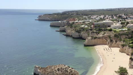 Drone-flies-over-Porches-Lagos-beach-lines-with-epic-coastal-cliffs-on-a-bright-blue-sunny-day,-Aerial-Flyover