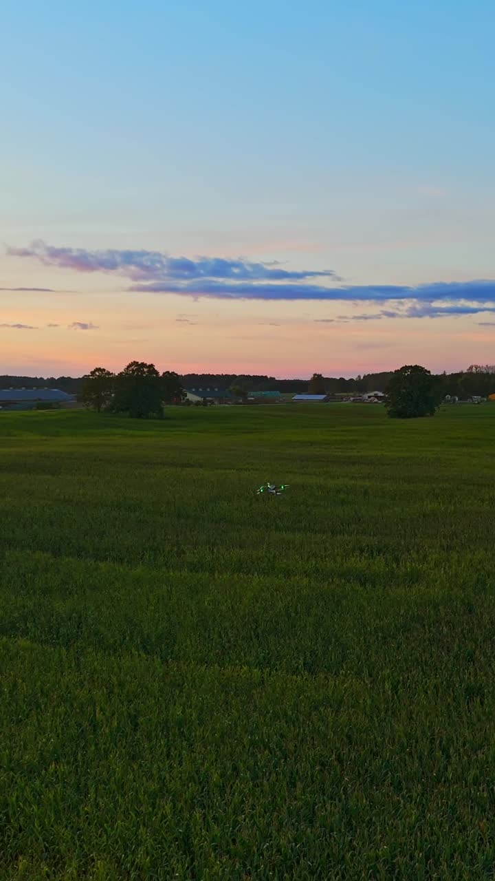 Agro-drone seeding or spraying crops at sunset in a rural landscape
