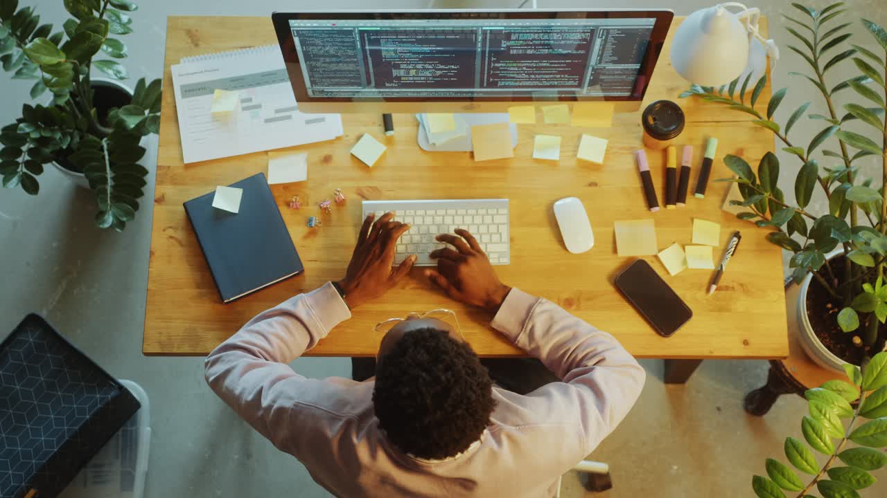 Top Down of Programmer Coding on Computer at Desk in Office