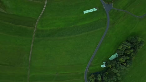 aerial drone top down shot over lush green grasslands alongside village cottages on a cloudy day