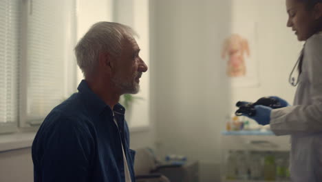 senior man visiting cardiologist in clinic close up. woman doctor checking pulse