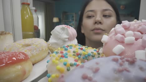 woman looking at delicious donuts and pastries in refrigerator