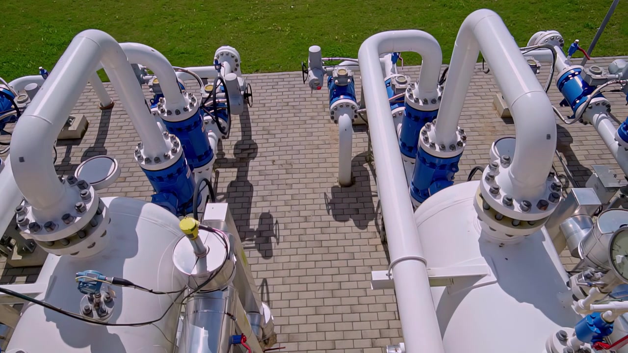 Impianto di lavorazione del gas naturale con tubi bianchi, valvole blu e serbatoi di stoccaggio a pressione