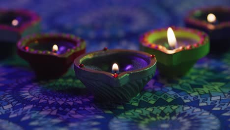 velas encendidas en ollas de arcilla decorativas en la mesa con patrones, apagadas, enfocadas en primer plano