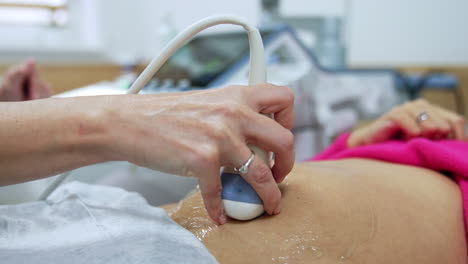 pregnancy examination at ultrasonic equipment. obstetrician moving the device by the little rounded belly of woman.