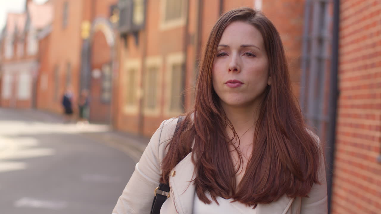 mujer al aire libre caminando a trabajar a lo largo de la calle de la ciudad alineada con casas