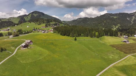 scenic aerial view of swiss alpine village with scattered chalets, green pastures, and forested hills in amden and arvenbüel near walensee, glarus, switzerland.