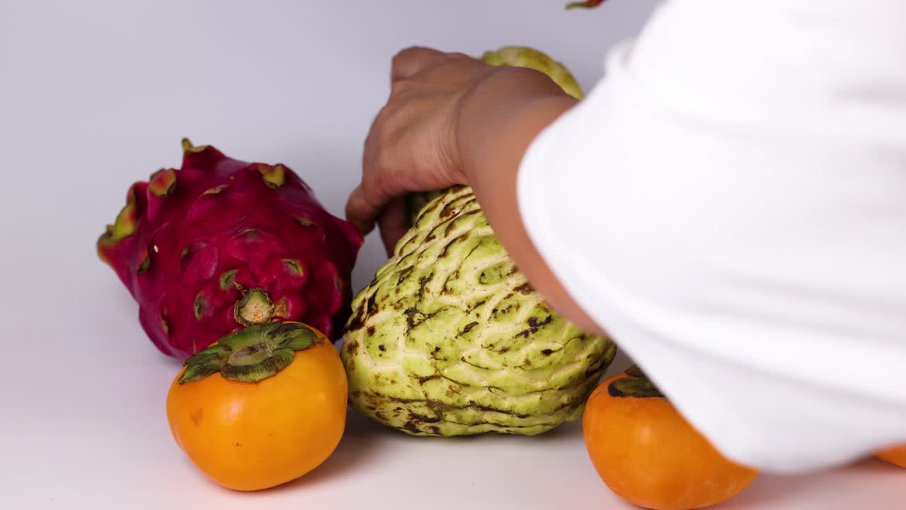 Mani che selezionano frutti da un assortimento colorato