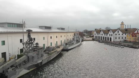 low alititude aerial footage from the side of two military ships next to a museum in karlskrona, sweden