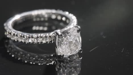 primer plano de un lujoso anillo de compromiso de diamantes que gira sobre una mesa de cristal