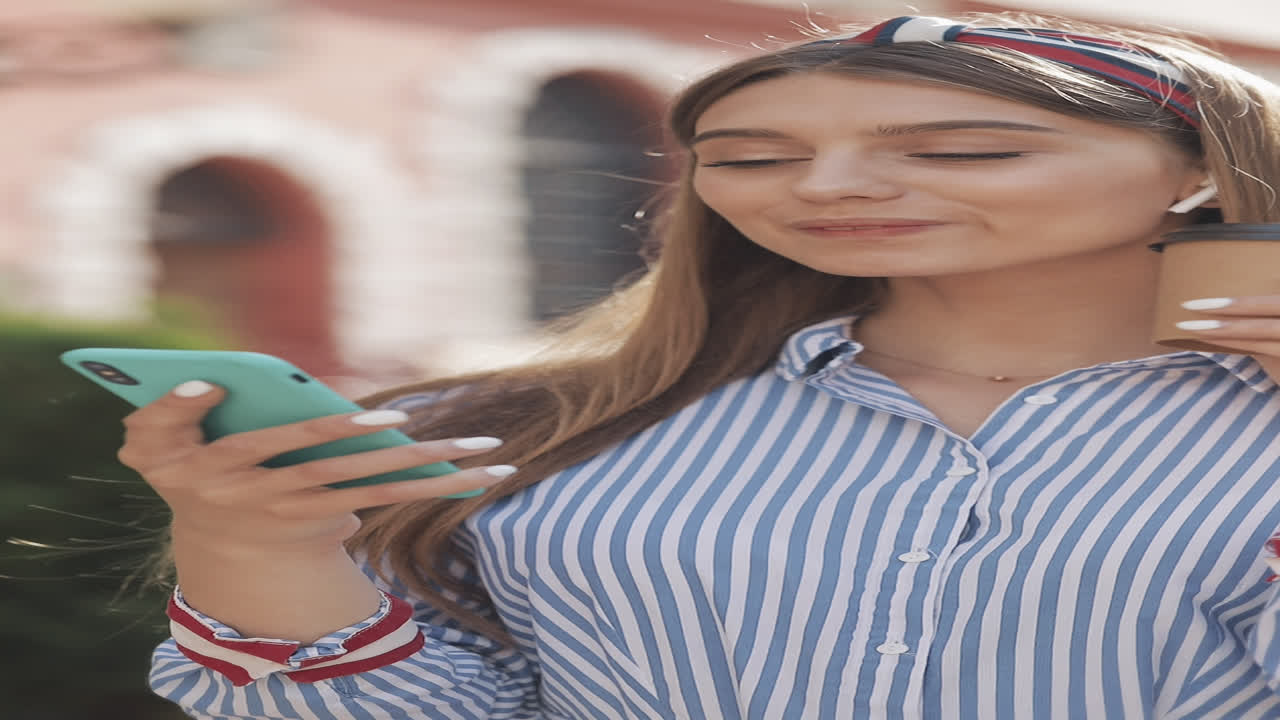 Giovane donna beve caffè e sorride mentre usa lo smartphone all'aperto