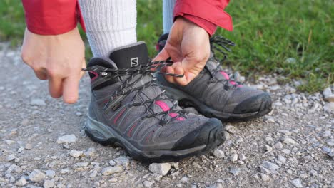 Hands-tying-shoelaces-on-gravel-path,-outdoors