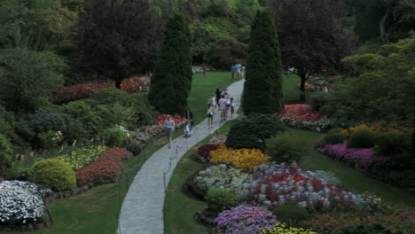 a panning shot overlooking intricate flowerbeds, landscaping, and people in the butchart gardens