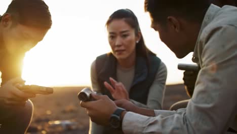 a group unites in their quest for discovery, analyzing data from mobile devices under the warm glow of a sunset in a natural environment