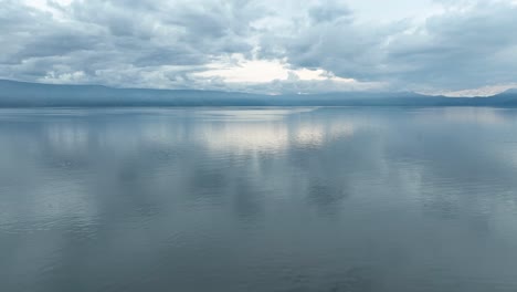 Aguas-Tranquilas-Del-Lago-Toba-Bajo-Un-Cielo-Suave,-Ambiente-Tranquilo-Y-Reflexivo,-Vista-Aérea