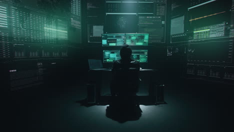 in una stanza buia con più monitor che mostrano dati e codici di hacker.