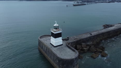 Holyhead-breakwater-lighthouse-longest-concrete-coastal-sea-protection-landmark-aerial-view-descending-push-in-slow