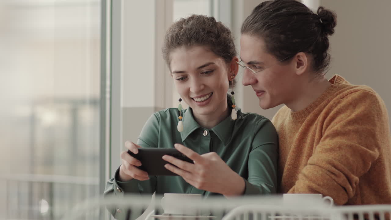 Young Man and Woman Using Smartphone in Restaurant