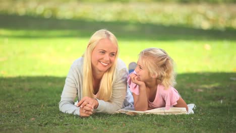 young woman lying on the grass with her daughter