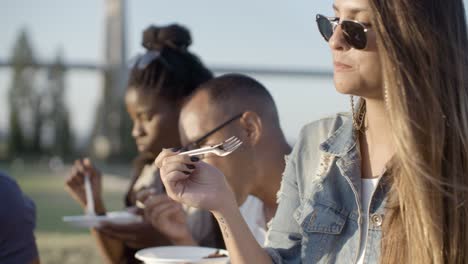 slow motion shot of smiling woman eating delicious cake in park