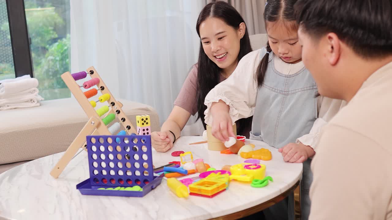 家族が明るく居心地の良いリビングルームで一緒に知育ゲームを楽しんでいます。
