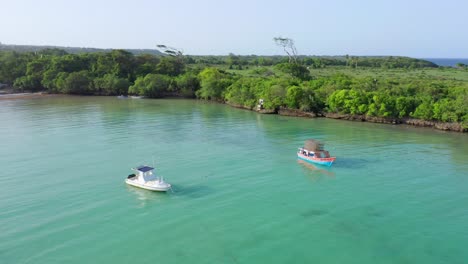 Two-Small-Fishing-Motorboats-Sit-Anchored-in-Incredible-Clear-Blue-Waters-of-Playa-Dimante-with-Tropical-background-in-Dominican-Republic