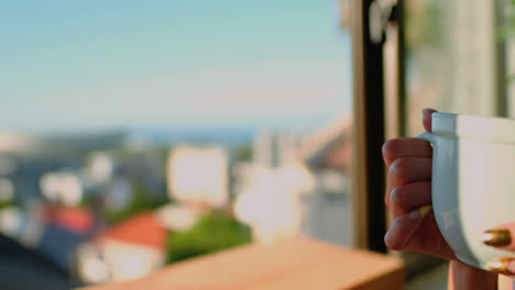 Woman-having-cup-of-coffee-and-looking-through-window-4k