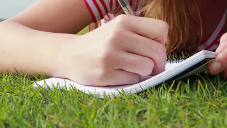 pretty young student lying on the grass studying