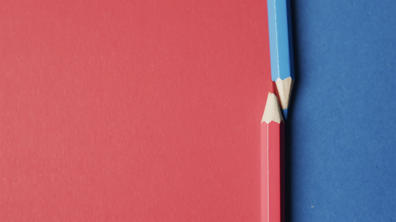 빨간색과 파란색 배경에 복사 공간과 함께 파란색과 빨간색 크레이온의 오버헤드 뷰, 느린 동작