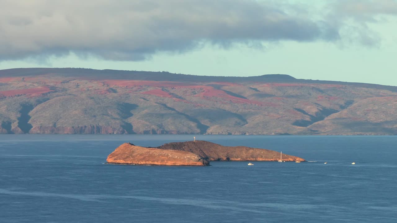 Smooth aerial orbit of Molokini Crater at sunrise, with a white tour boat approaching the volcanic islet. Perfect for travel, tourism, ocean conservation, and Hawaii-related storytelling