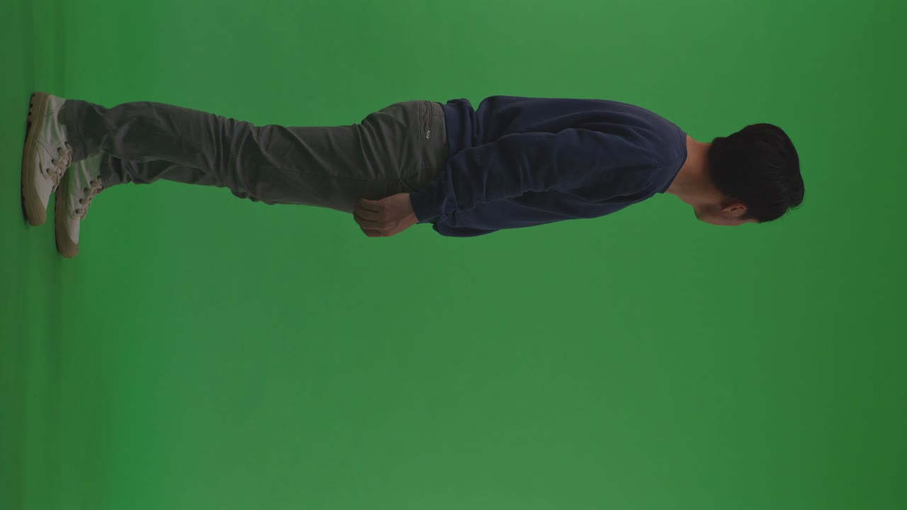 cuerpo completo vista lateral de angustiado refugiado asiático hombre de pie y mirando a su alrededor se protege de la guerra en el fondo de la pantalla verde