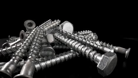 pile of metal screws on a black background