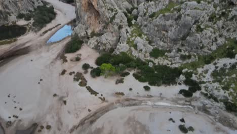 tilting drone shot of a canyon with water at the bottom at sa calobra, mallorca, spain