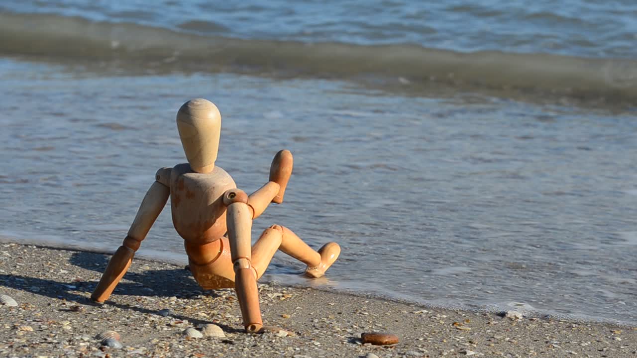 Houten pop op het strand. Opnames op het strand