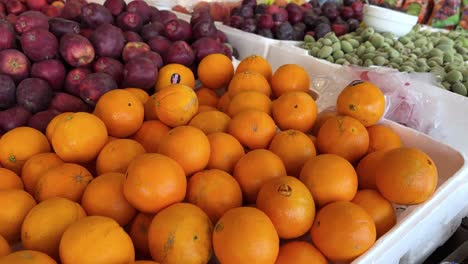 colorful 4k shot of fresh oranges, apples, and plums at an outdoor market stand. perfect for themes of health, freshness, nutrition, and natural produce.