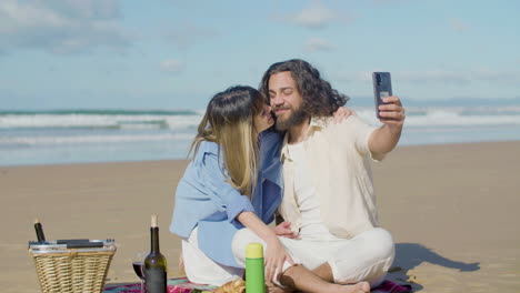 una joven pareja romántica tomando una selfie en la playa