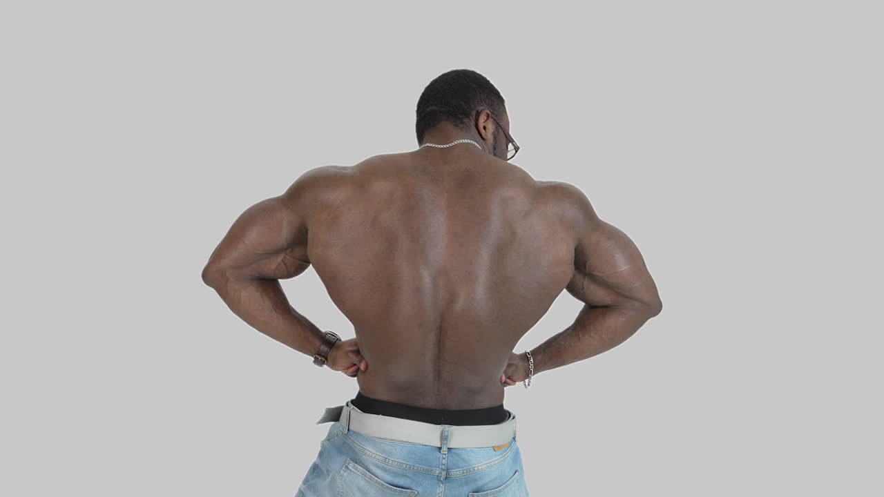 Sportsman with dark skin shows his back muscles. Muscular afro american athlete with trained body isolated on white. Back view.