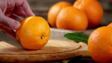 hands men cut a fresh orange into two halves.