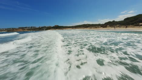 FPV-Drohne-Reitet-Die-Klare-Blaue-Brandung-An-Einem-Wunderschönen-Strandtag-Mit-Blauem-Himmel-Und-Hoher-Geschwindigkeit