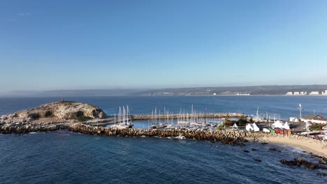 aerial shot of sailboats yachts moored in a harbor near small rock at daylight in chile, south america