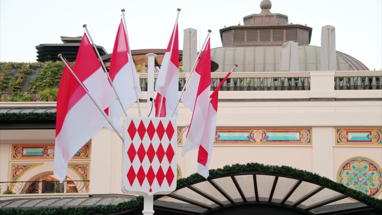 Monte Carlo, Monaco - October 24, 2024: The coat of arms of Monaco and multiple flags waving in front of the Monte Carlo Casino