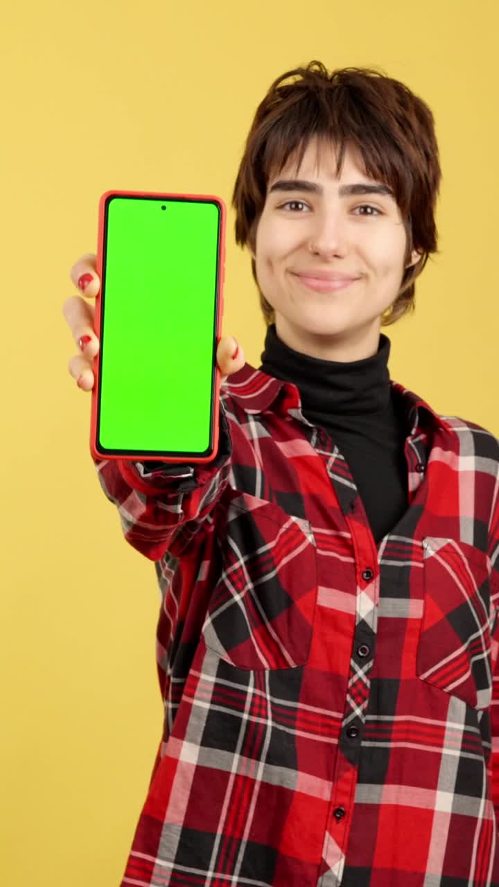 mujer joven sosteniendo un teléfono inteligente con pantalla verde